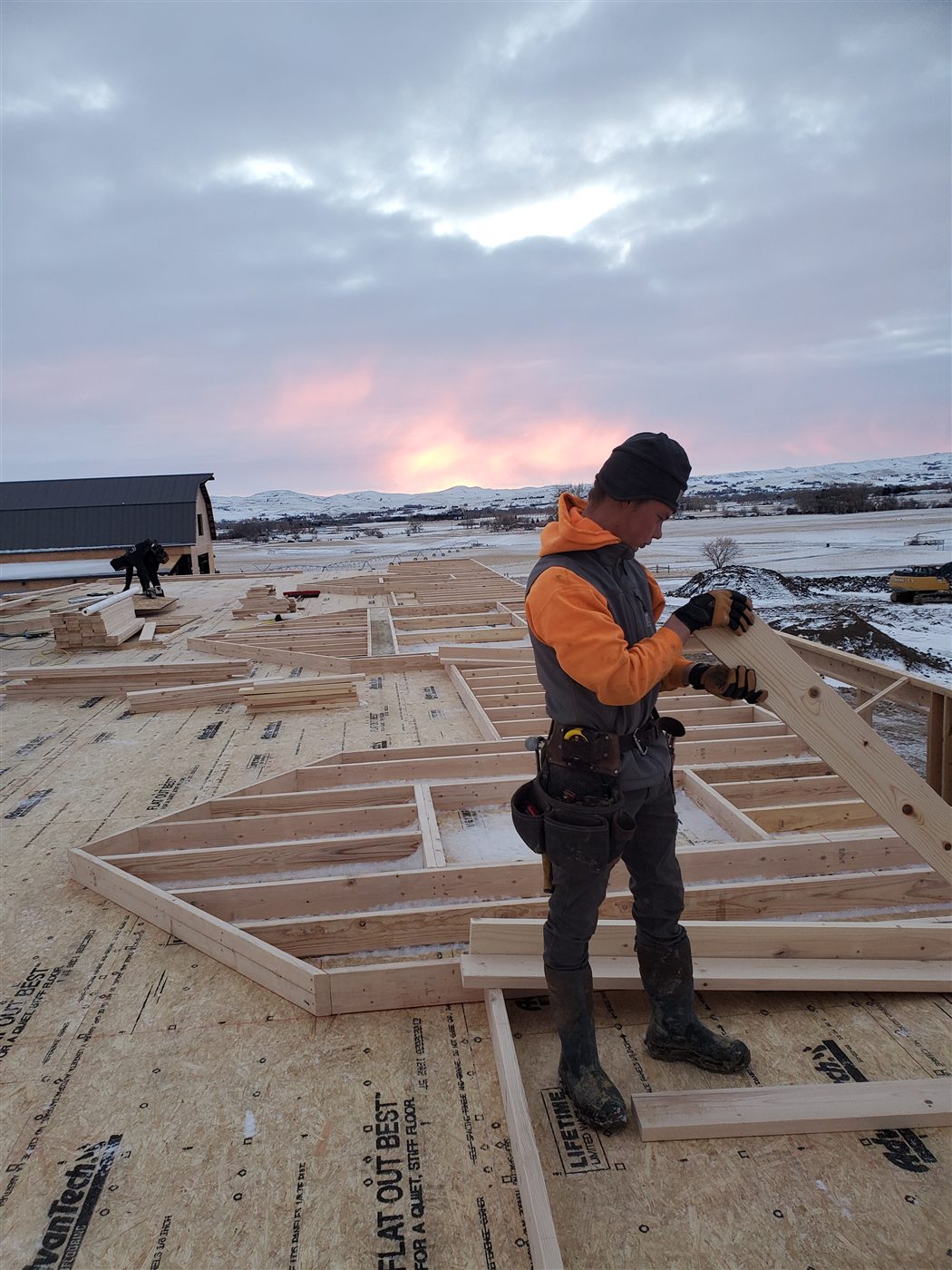 A Build It Brothers builder framing at sunrise